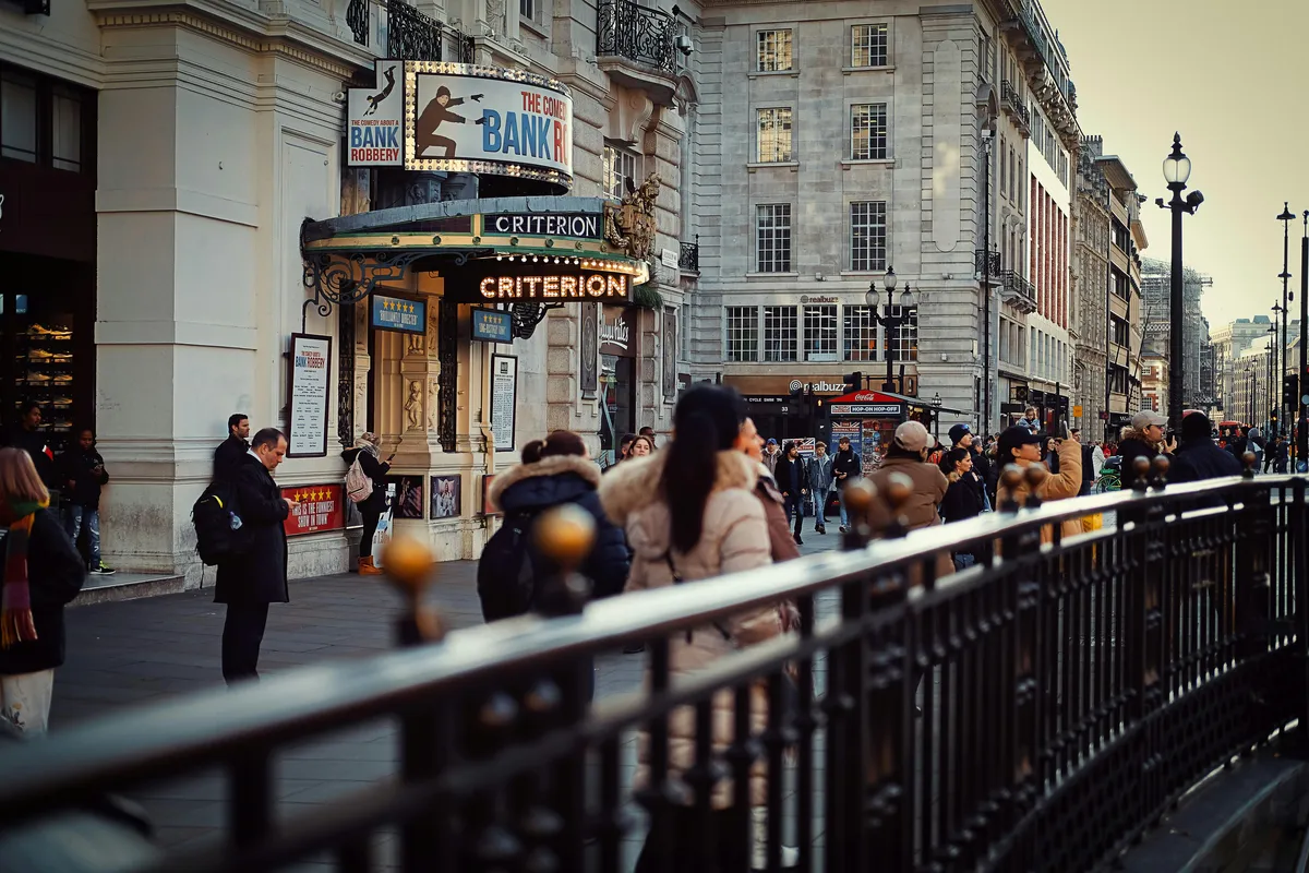 London's West End at dusk, with glowing Criterion theatre marquee, setting the scene for a memorable pre and post theatre dinner in London at Aki London on Cavendish Square
